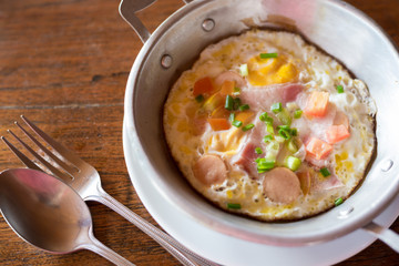 breakfast with fried eggs in a pan on wooden background