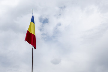 Romanian flag on flagpole blowing in wind isolated on blue sky