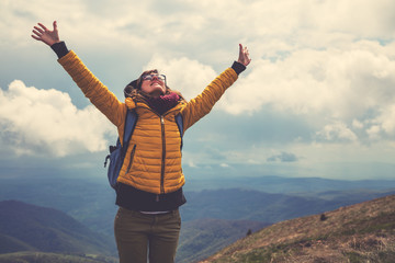 Girl with rucksack on the top of the hilly landscape.