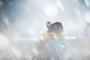 Woman with praying hands in snowy / rainy cold day.