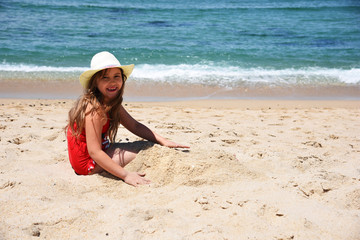 A little girl in a red bathing suit admires the ocean. Porto. Portugal.