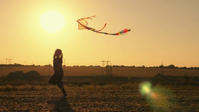 Beauty young girl running with kite at sunset