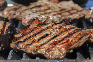 Meat steaks are cooked on a hot grill with smoke. Close-up