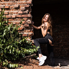 beautiful young woman standing near the brickwall in abandoned building