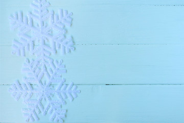 Christmas background, artificial snowflakes on a light blue  wooden surface.