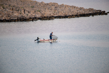 Old traditional fisherman in Croatia on a small wooden boat catching fish with fishing cage, pod