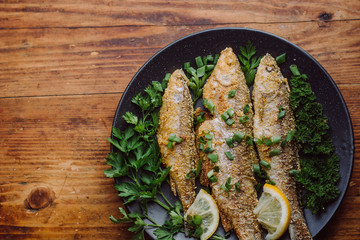 Fried fish in a plate on the wooden table