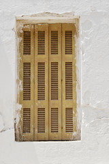 Abandoned stucco white wall with closed window.