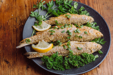 Fried fish in a plate on the wooden table