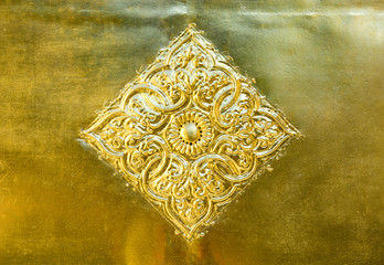 flower and leaf pattern in Thai Lanna style carved on gold metal plate background decorate on golden pagoda in Buddhist temple