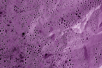 Condensation drops on plastic transparent material in purple tone.