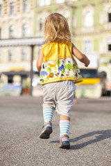 Kind läuft in bunter Mode auf Platz. Fashionable child running on urban city place.