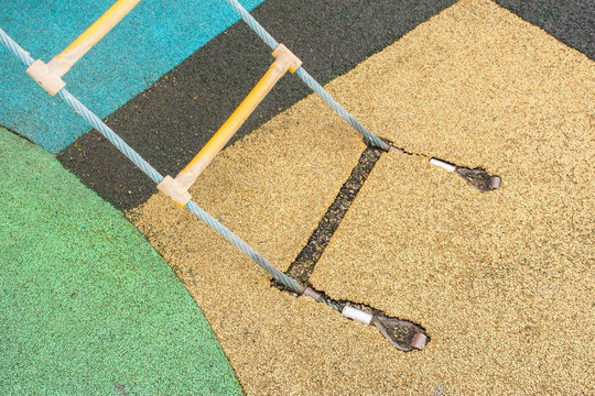 Fastening of a rope ladder to a rubber covering on a playground in the street