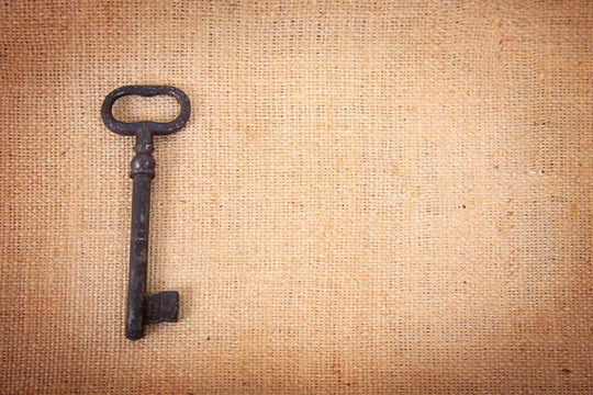 An ancient metal key on the background of sacking.