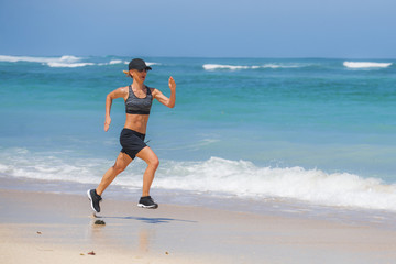 young happy and attractive sport runner woman doing running workout sprinting on tropical paradise beach showing fit and athletic body in wellness fitness concept