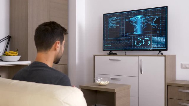 Man playing a strategic video game on the console on big screen TV. Back view. Dolly slider 4K footage