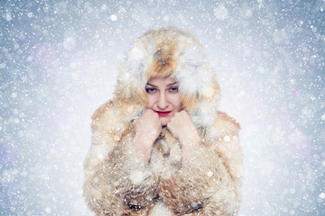 Frozen young woman in a fox fur coat, cold, snow, frost, blizzard