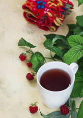 Raspberry tea with leaves and raspberries, warm scarf on a light background