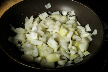 closeup fried onion in black frying pan