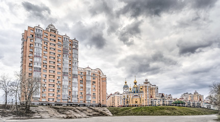 Modern buildings, and the Birth of Christ Church in the Obolon district of Kiev, Ukraine, near the Dnieper River, under a stormy and cloudy sky