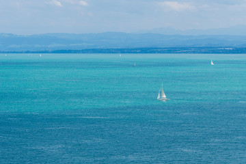 Sailboats on blue water with mountains behind