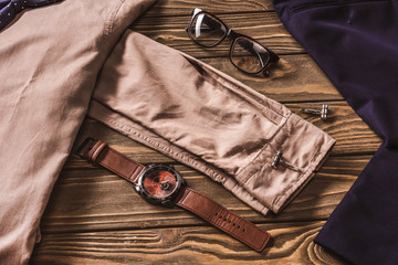 close up view of stylish clothing, eyeglasses and wristwatch on wooden surface