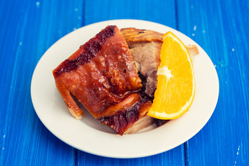 roasted piglet with orange on white plate