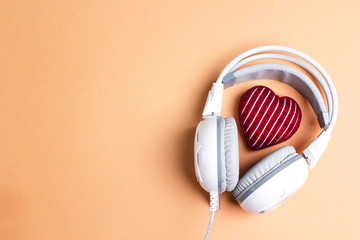 White headphones with red knitted heart and copy space. Top view, flat lay