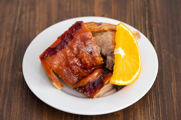 roasted piglet with orange on white plate