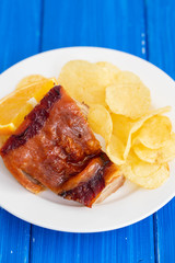 roasted piglet with potato chips and orange on white plate