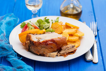 roasted piglet with potato chips and orange on white plate