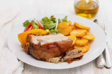 roasted piglet with potato chips and orange on white plate