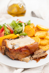 roasted piglet with potato chips and orange on white plate