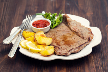 grilled meat with potato and sauce on white dish