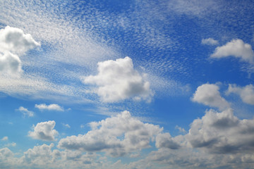 A lot of white clouds of different types: cumulus, cirrus, layered high in blue sky on a sunny day