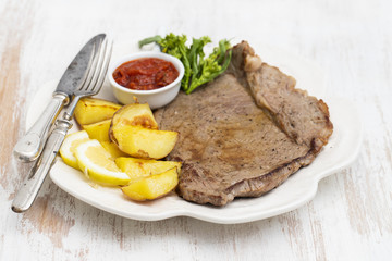 grilled meat with potato and sauce on white dish
