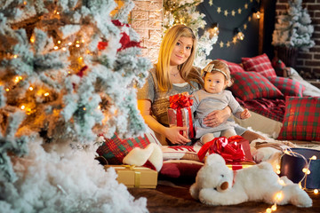 Mother with baby in a hat of Santa Claus in the Christmas room Christmas day.