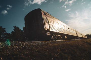 Abstract blurred motion of train with railway carriage in sunlight close up. Background with locomotive on railroad at sunny day with copy space.