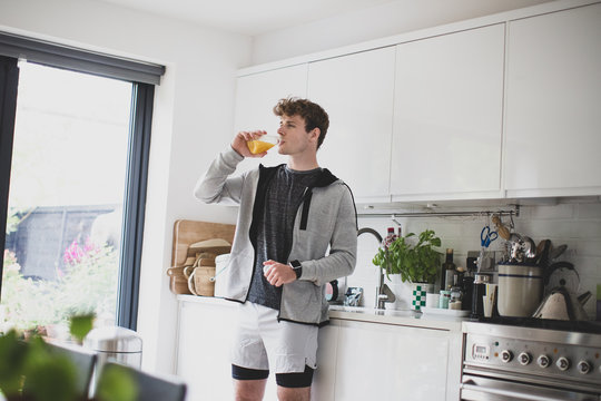 Young adult male drinking orange juice before after a run