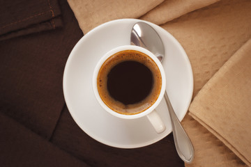 Homemade cup of espresso coffee with dark and light color napkins. Top view.