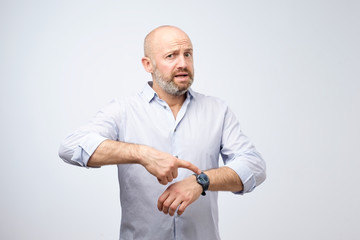 Mature european businessman impatiently pointing to his watch. Why are you late concept.