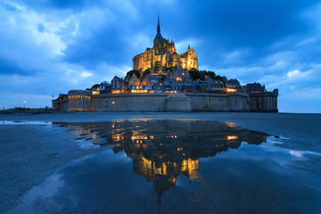 Beautiful view of historic landmark Le Mont Saint-Michel in Normandy, France, a famous UNESCO world heritage site and tourist attraction, at twilight in the blue hour after sunset