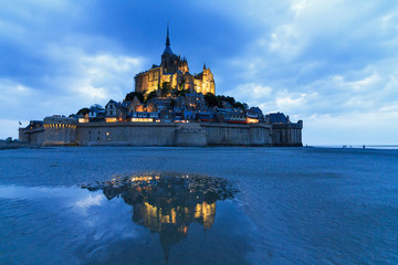 Beautiful view of historic landmark Le Mont Saint-Michel in Normandy, France, a famous UNESCO world heritage site and tourist attraction, at twilight in the blue hour after sunset