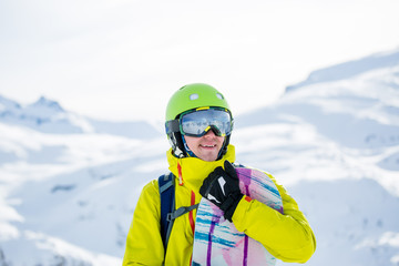 Photo of sportive man with snowboard against background of mountains