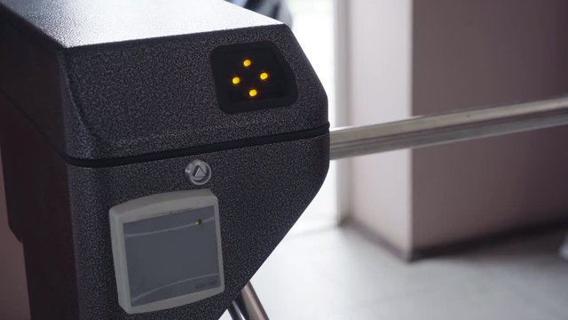 An entrance turnstile with access green sign. Security barrier