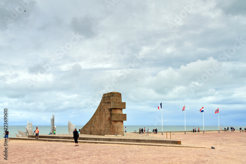 Tourists Visit The D Day Monument On Omaha Beach In Normandy France Tourists Visit The D Day Monument On Omaha Beach In Normandy France