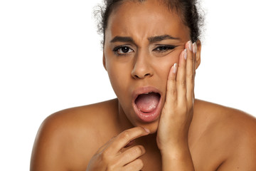 portrait of young dark-skinned woman with tooth ache on white background