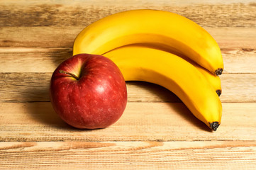 still life of bananas and red apple on a wooden background with copy space