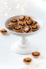Christmas mince pies on a white stand with festive lights at thhe background
