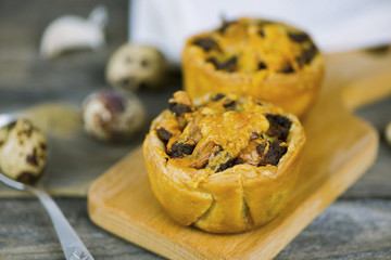 Baked puff pastry with meat stuffing and cheese on a wooden board